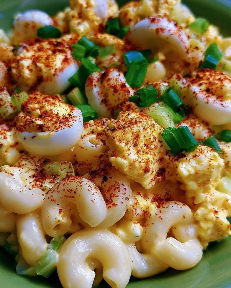 Bowl of deviled egg pasta salad garnished with herbs and eggs